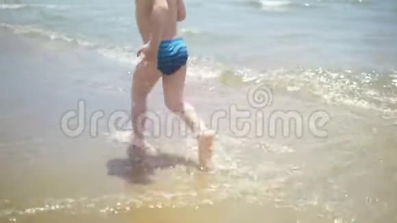 镜头移向后面在海滩上奔跑一个小男孩视频的预览图