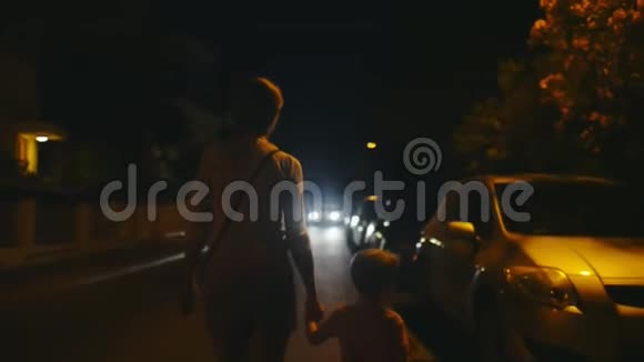 妈妈和儿子牵着手晚上在大街上停着车视频的预览图
