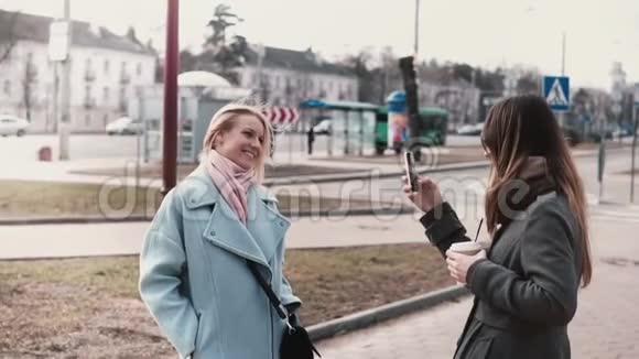 两个白人朋友互相拍照漂亮的女孩一起出去玩拍智能手机照片慢动作视频的预览图