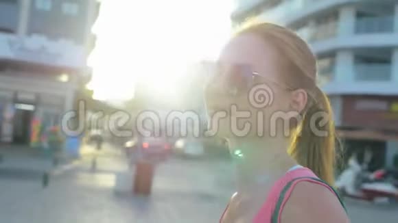 戴墨镜的迷人微笑女孩站在大城市的街道上视频的预览图
