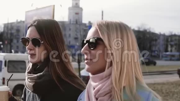 慢动作两个白人女人谈话20多岁的女士穿着时髦的衣服戴着太阳镜在街上笑着聊天视频的预览图