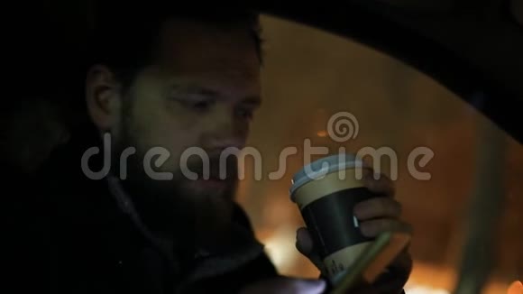 大胡子男人喝咖啡在车里用电话视频的预览图