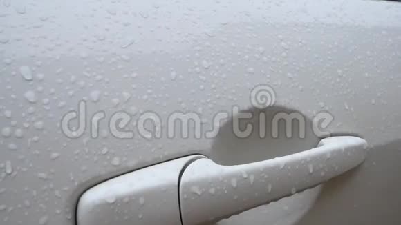 特写上车白色汽车门把手上的雨滴视频的预览图