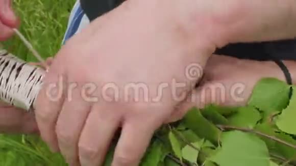 男人手系着桦树枝为桑拿做扫帚视频的预览图
