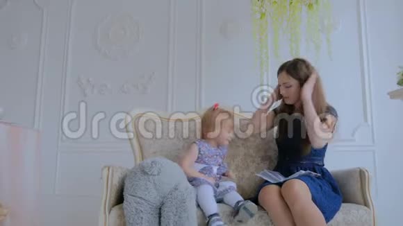 年轻的母亲和她的小女儿正在看照片视频的预览图