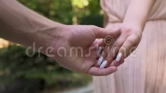 男跟女朋友牵着她的手特写在城市公园约会关系视频的预览图