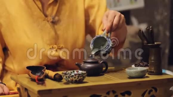 女性手把草药叶放在茶壶里表演历史艺术传统视频的预览图