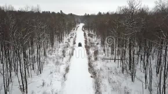 6x6越野车的鸟瞰图在冬季森林的雪覆盖道路上正面可见风景视频的预览图