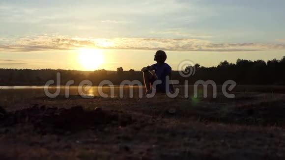 浪漫的男人在日落时分坐在湖边喝茶视频的预览图