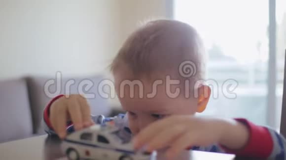 悲伤孤独的小男孩在桌子上玩玩具车视频的预览图