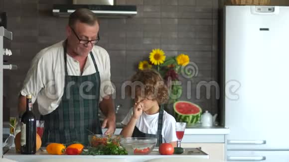 祖父和孙子在厨房里一位老人给了男孩一把菜刀教你如何切一把视频的预览图