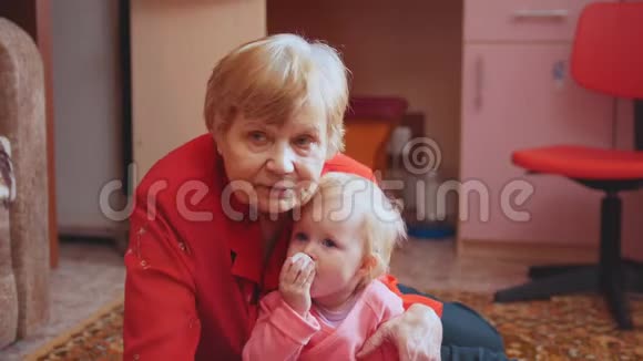 小女孩和奶奶在地板上玩耍奶奶拥抱和亲吻孙女视频的预览图