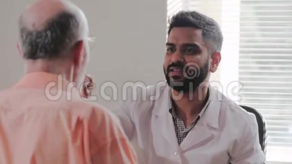 年轻的印度男医生皮肤科医生检查病人的眼球视频的预览图