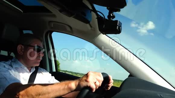 一个穿着白衬衫戴太阳镜的人正在开车视频的预览图