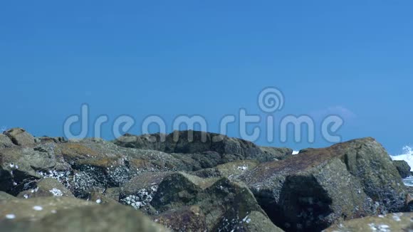 海岸上的石头和蓝天景观上的水波在岩石海滩上海浪拍打着海岸视频的预览图