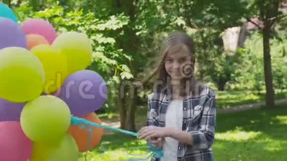 快乐的小女孩在公园里玩着五颜六色的气球视频的预览图