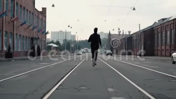 人在一条老街中间跑得很快实时拍摄自由摄像机跟随运动员在电车轨道之间视频的预览图