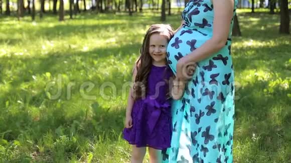一个小女孩在公园里拥抱她怀孕的妈妈视频的预览图