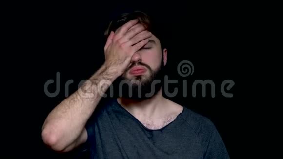 一幅失望而沮丧的人的肖像胡子用手掌遮住他的脸孤立在黑色的背景上失望视频的预览图