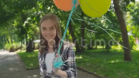 快乐的年轻女孩在公园里玩着五颜六色的气球4K视频的预览图