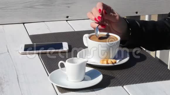 女性手在户外咖啡馆里用茶匙搅拌咖啡视频的预览图