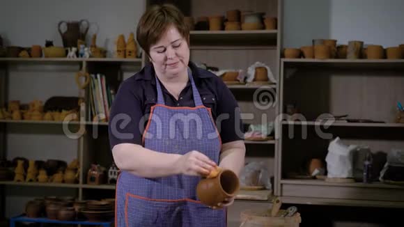在她工作的车间里陶器师傅用潮湿的海绵陶罐擦拭那女人做了盘子出售视频的预览图