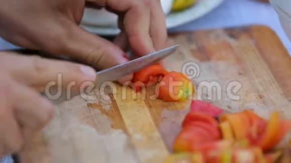 男人在切割板上切新鲜西红柿野餐城市公园健康的生活方式视频的预览图
