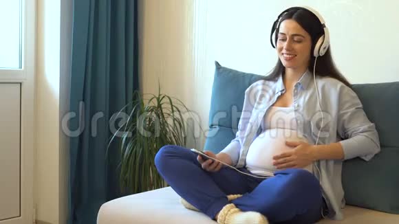 孕妇用耳机听音乐视频的预览图