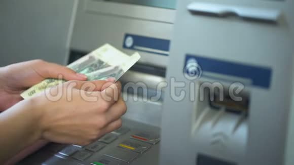 数着从ATM机取款的俄罗斯卢布的女人把现金放进粉红色的钱包里视频的预览图