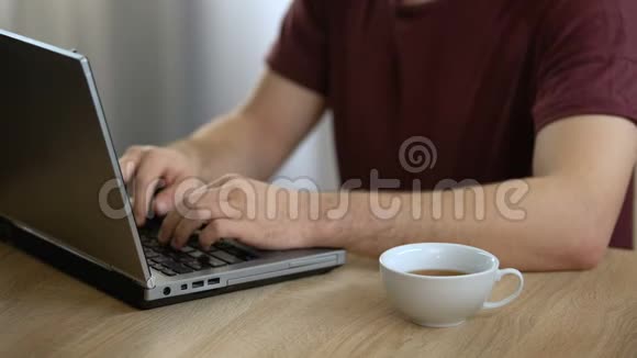 男作家打字手提电脑在家喝茶自由职业记者视频的预览图