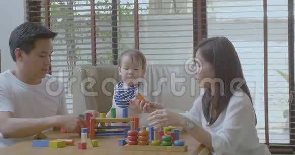 快乐的妈妈爸爸和小亚洲男孩在家玩木玩具视频的预览图