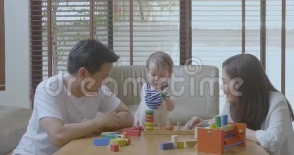 快乐的妈妈爸爸和小亚洲男孩在家玩木玩具视频的预览图