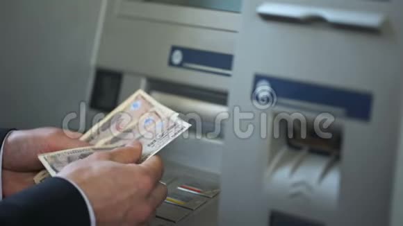 一个人从ATM机取款把现金放进钱包旅游视频的预览图