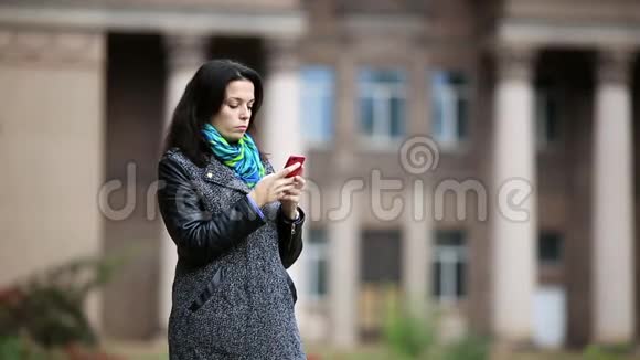站在公园中央的迷人的年轻女子用她的智能手机录音视频的预览图
