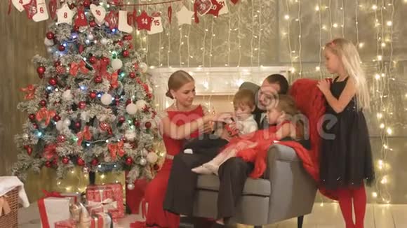 有三个孩子坐在圣诞树旁的幸福家庭视频的预览图