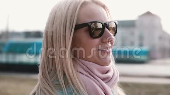 美丽的金发白种人女人的肖像快乐的微笑漂亮的20岁女孩在时尚的太阳镜侧视视频的预览图