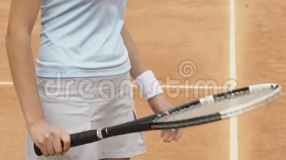 女孩用球拍打网球在球场上热身关闭视频的预览图