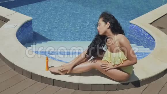 红唇迷人的黑发女郎在泳池附近用化妆水涂抹自己视频的预览图