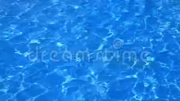 在有阳光反射的游泳池中蓝色和明亮的波纹水面的缓慢运动视频的预览图
