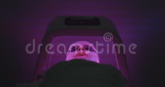 皮肤护理和面部治疗带面罩和眼镜的女性LED照明程序4K录像前景视频的预览图