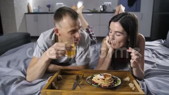快乐的情侣在床上吃早餐煎饼视频的预览图