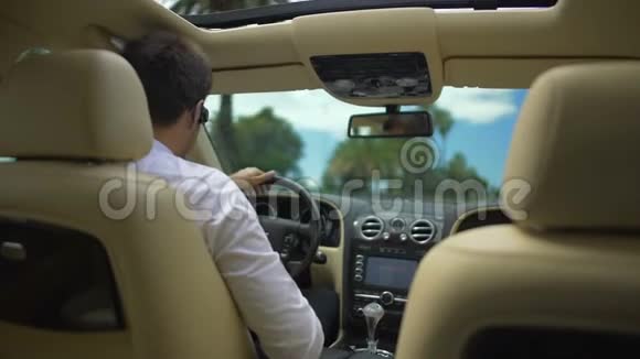 商务人士驾驶汽车通过无线耳机和科技电话交谈视频的预览图