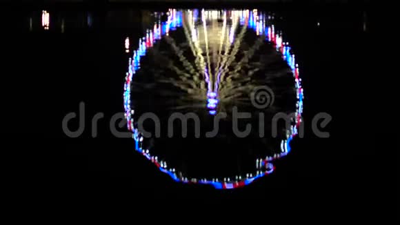 摩天轮在夜间用灯光照明反映水娱乐视频的预览图