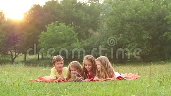 可爱的孩子们一起在草坪上看书夏天美好的下午慢动作视频的预览图