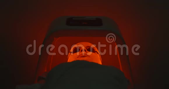 LED灯治疗年轻女子的脸与面具和眼镜躺在特殊的小屋在水疗沙龙变化视频的预览图