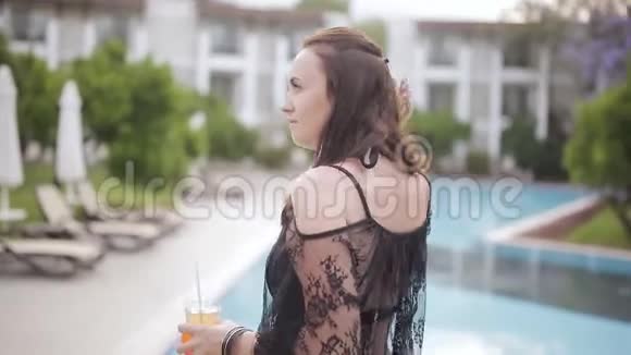 带着鸡尾酒的女人在泳池边散步视频的预览图