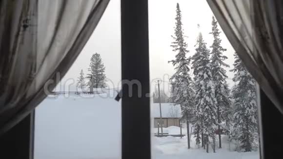 窗外看着外面的雪落在树上房子在晴天的冬天慢动作3840x2160视频的预览图