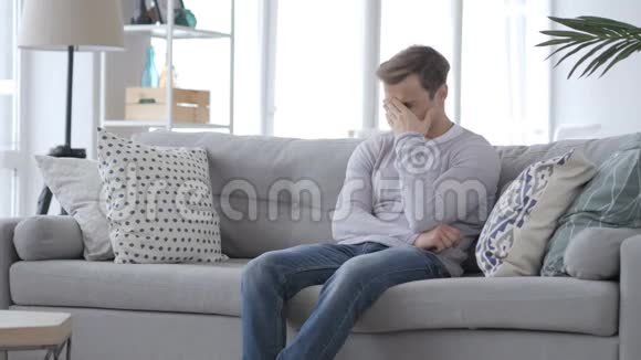 成年男子愤怒地坐在沙发上感到沮丧视频的预览图