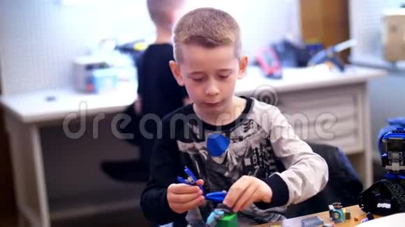 这个10岁的男孩从立方体盘子电路电线中扮演设计师小发明家创造机器人视频的预览图