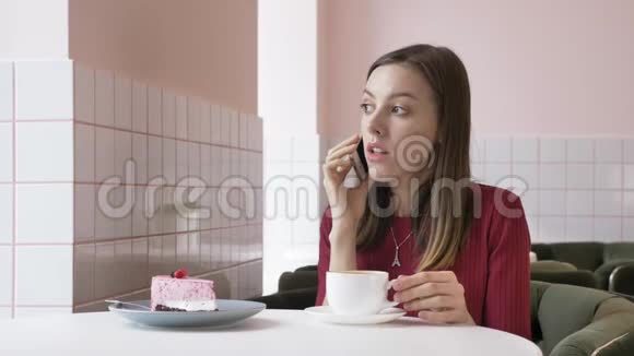 一个年轻漂亮的黑发女孩坐在咖啡馆里用智能手机接电话打电话视频的预览图